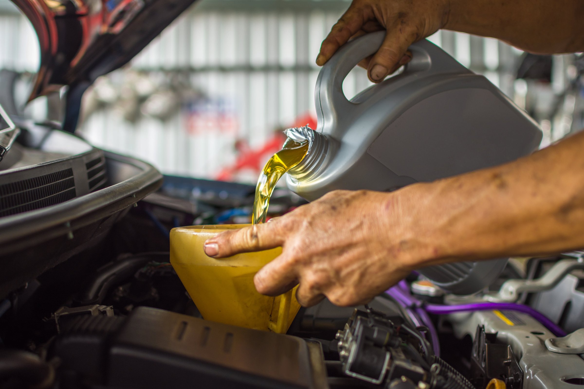 Car mechanic fills a fresh lubricant engine oil
